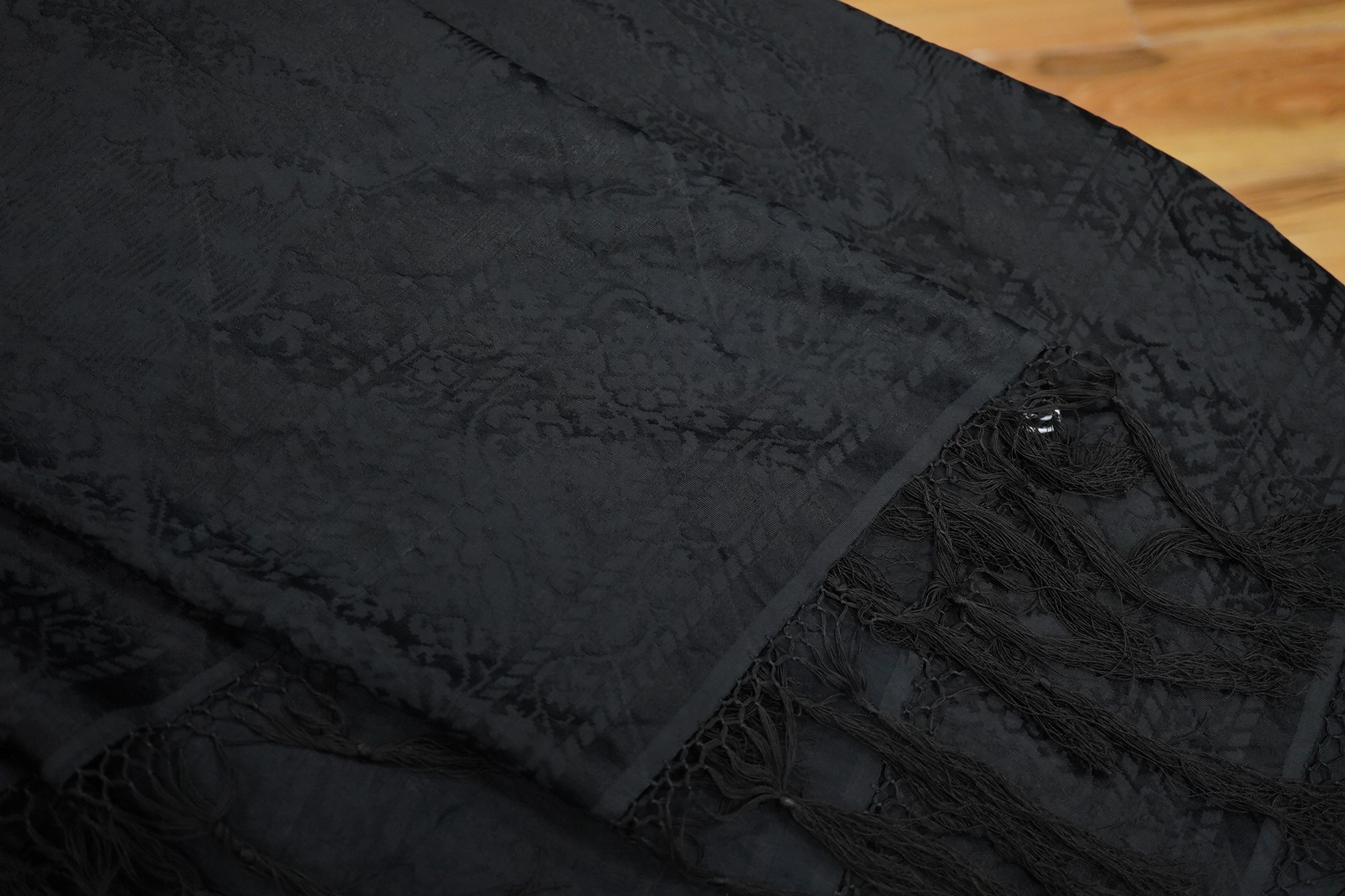 A Edwardian black silk damask paisley patterned shawl. Possibly a mourning shawl.178cm x 156cm. Condition - one small hole, otherwise good.